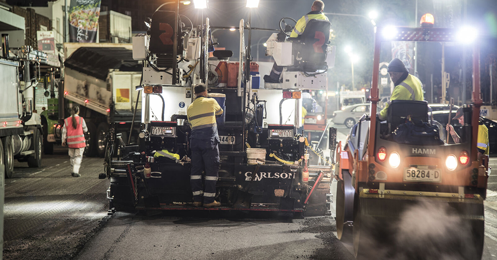 Night roadworks - hotmix being laid on city street.