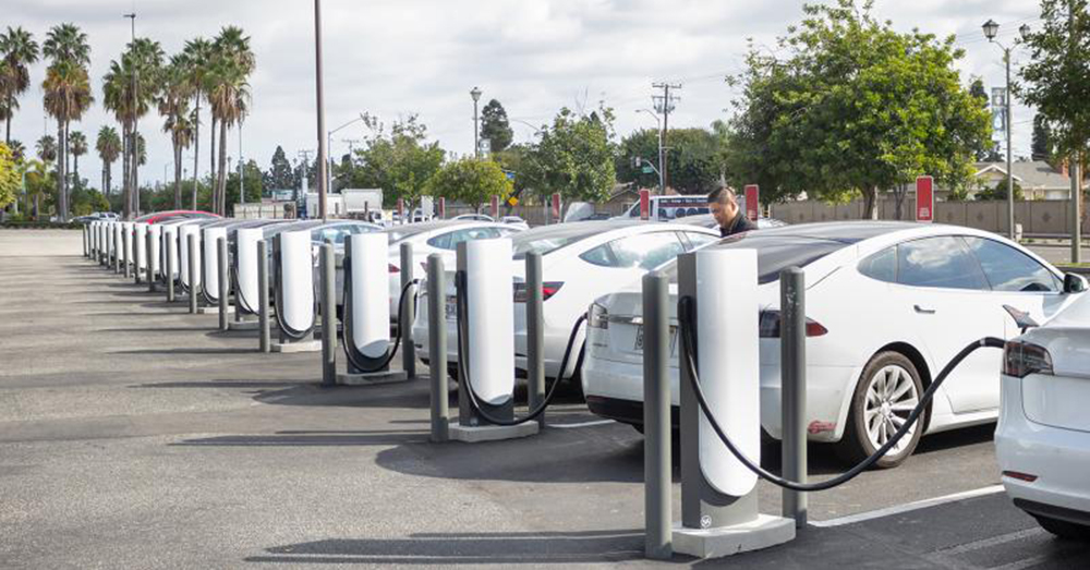 A wide shot of several Tesla cars parked in a Tesla Supercharger pump station.