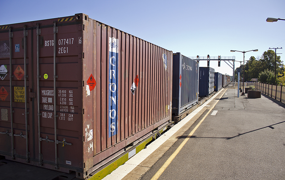 A train carrying freight containers passes through Junee Railway Station.