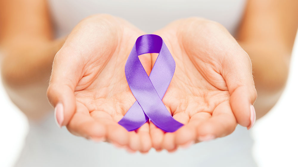 A womans outstretched arms with a purple ribbon in her hands.