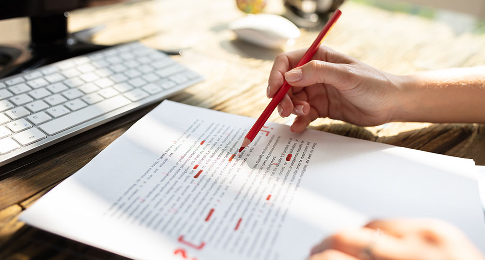 A person with a red pensil edits a typed piece of corresponsence.