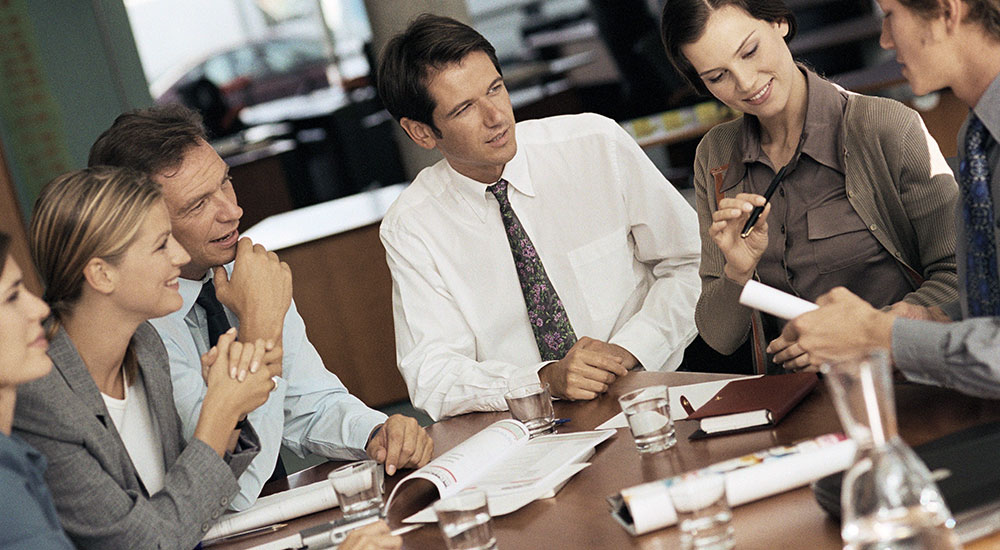 A group of people at a table in discussion in a business setting.