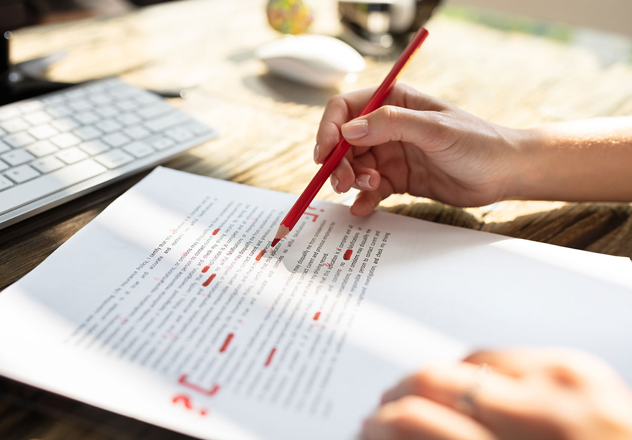 A person marks errors on an A4 page in red pencil.