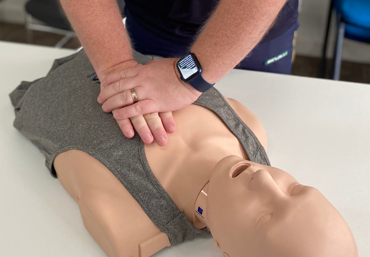 A trainer shows, on a first aid dummy, how to perform chest compressions as part of CPR.
