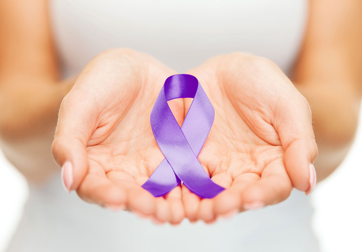 A woman's outstretched hands and in it is a purple ribbon.