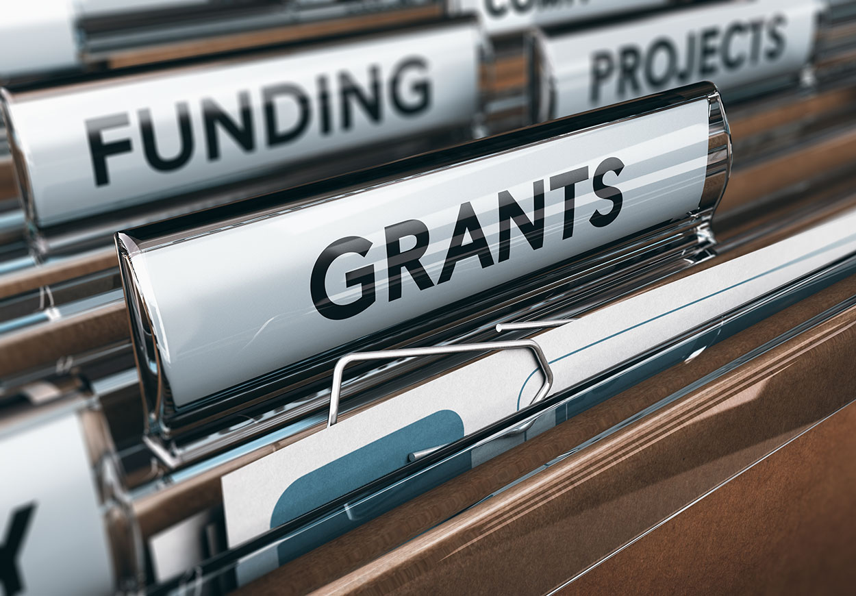 An open filing cabinet drawer with one file labelled "grants".