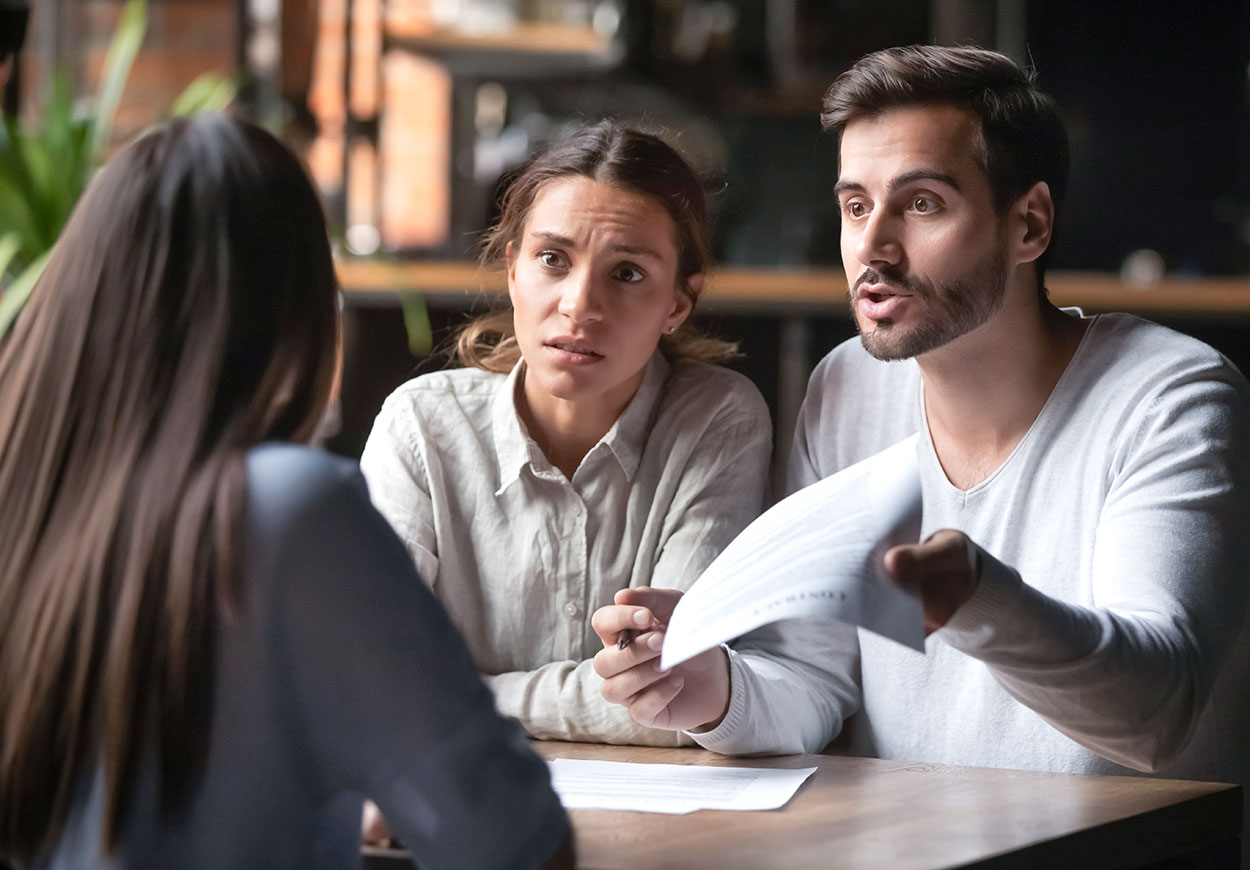 A customer service officer in a discussion with an aggrieved-looking couple.