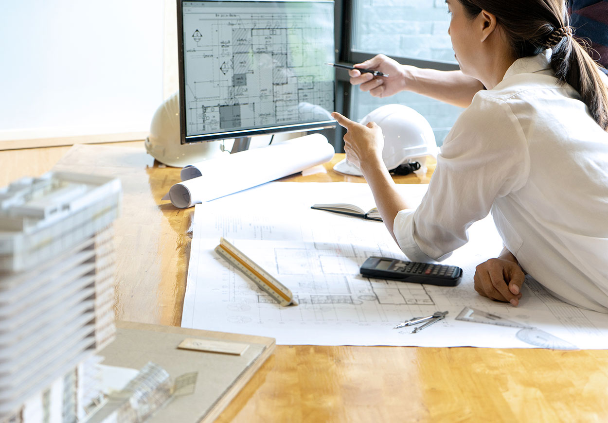 Two people discussing building plans displayed on a computer screen.