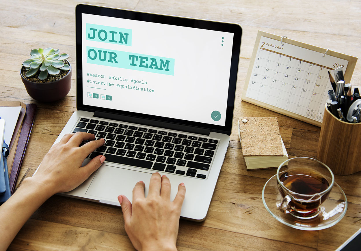 Hands on the keyboard of an open laptop and on the screen is a stylised inscription "Join Our Team".