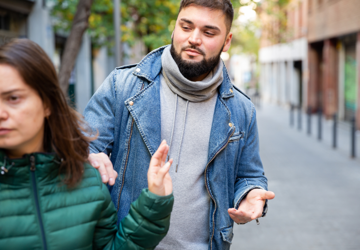 A woman brushes aside a nefarious-looking man who is touching her shoulder from behind.