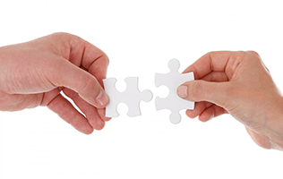 Hands holding two pieces of a jigsaw puzzle.