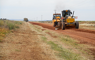 Graders grading a rural dirt road